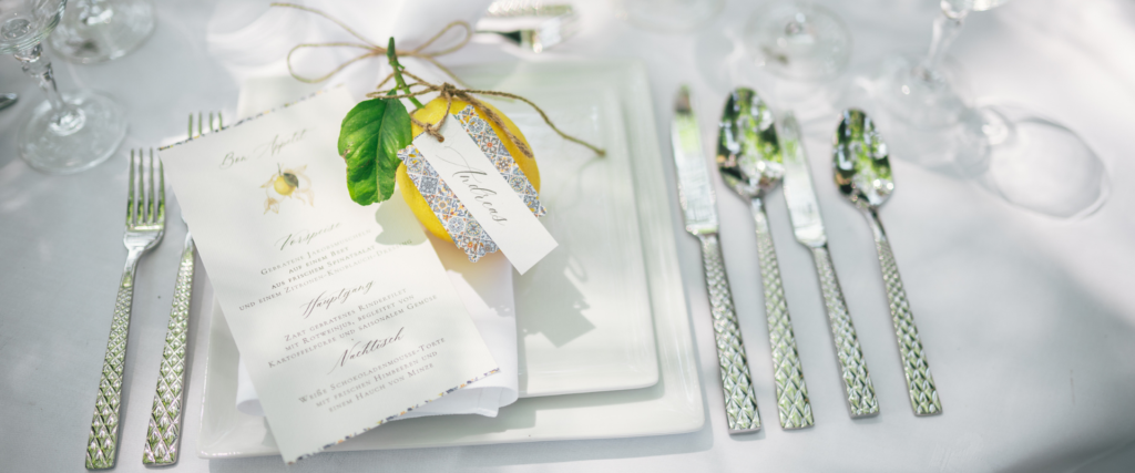 Eleganter Tischplatz mit Menükarte, Zitronen-Deko und gemustertem Silberbesteck – Hochzeitsdeko-Mietartikel von Partyladen von Voss
