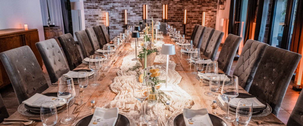 Lange festlich gedeckte Bankett-Tafel mit Samtstühlen, Kerzenlicht und Weingläsern – Event-Mobiliar von Partyladen von Voss